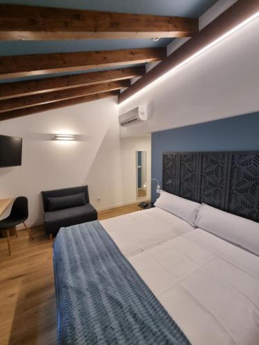 a bedroom with a large white bed and a chair at Hostal La Rúa in Estella