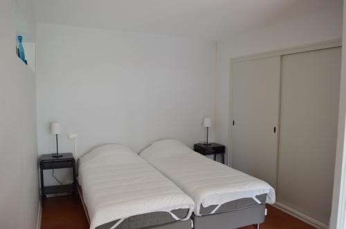 een slaapkamer met een bed met witte lakens en 2 lampen bij Appartement Pour 2 Personnes Vue Sur Le Port- Residence Jean Rameau in Hossegor