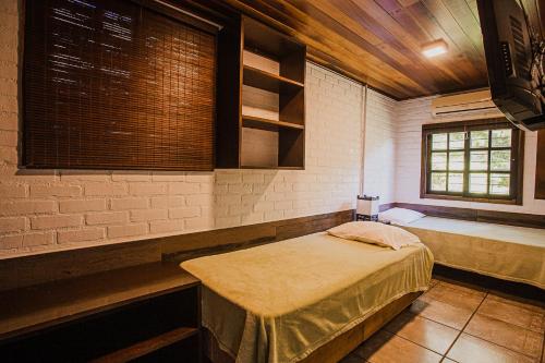 a room with a bed and two windows at Pousada Colina Verde in Garopaba