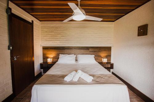 a bedroom with a bed with two white slippers on it at Pousada Colina Verde in Garopaba
