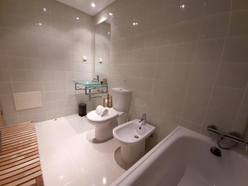 a bathroom with a toilet and a tub and a sink at Doce Mar in Cabanas de Tavira