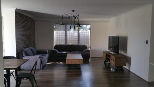 ein Wohnzimmer mit einem Sofa und einem TV in der Unterkunft Fremantle Colonial Home in Fremantle