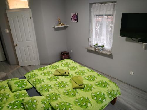 a bedroom with a bed with a green comforter at Fehérló Vendégház & Restaurant in Bük
