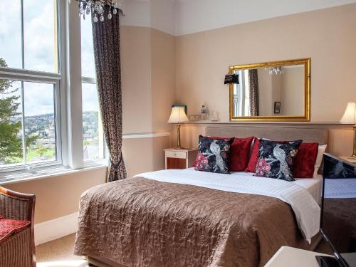 a bedroom with a bed with a mirror and windows at Court Prior Boutique B&B and Apartment in Torquay