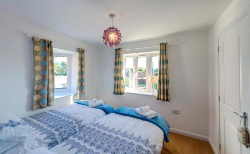 a bedroom with a blue and white bed with a chandelier at Kittiwake Cottage Camber Sands in Camber