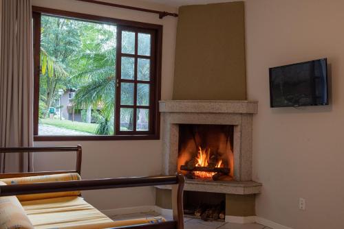 sala de estar con chimenea y TV en Hotel Vila Verde, en Nova Friburgo