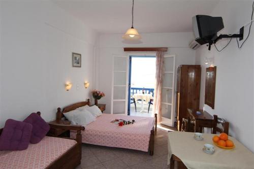 a bedroom with two beds and a living room with a table at Studios Vagos 2 in Agios Prokopios