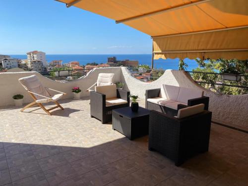un patio con sillas, mesas y una sombrilla en Vista Stromboli, en Paola