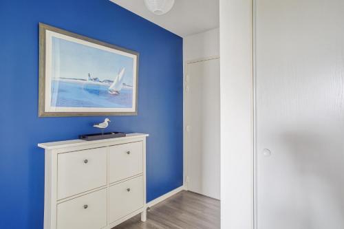ein blaues Zimmer mit einer Kommode und einem Gemälde an der Wand in der Unterkunft Ker Eno in Dinard
