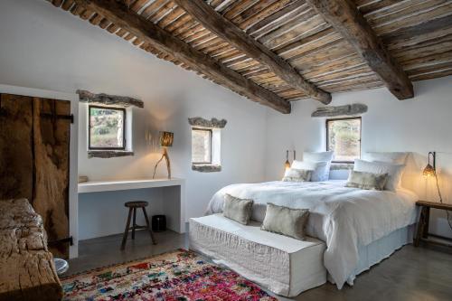 a bedroom with a large white bed and windows at Le Domaine du Castellas in Sivergues