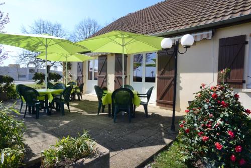 a patio with green tables and chairs and umbrellas at Hotel inn Dijon-Quetigny in Quétigny