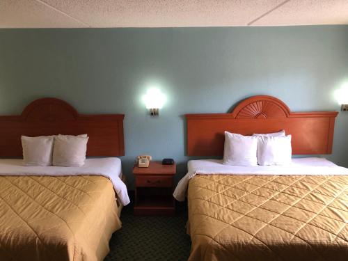 a hotel room with two beds and two night stands at Rodeway Inn Joint Base Andrews Area in Camp Springs