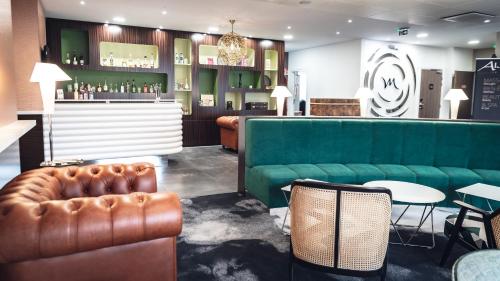 a bar with a green couch and a table and chairs at Mercure Belfort Centre in Belfort