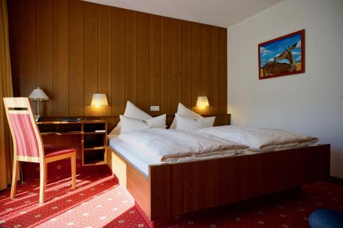 a bedroom with a bed and a desk and a chair at Sporthotel Wilder Kaiser in Oberaudorf