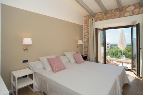 a bedroom with a large white bed with pink pillows at Villa Ferrer de SHorta in S'Horta