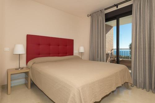 una camera con un grande letto con testiera rossa di Spacious 3 bedrooms apartment side sea view a Torrox Costa