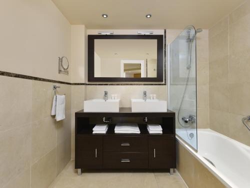 La salle de bains est pourvue de 2 lavabos, d'une baignoire et d'un miroir. dans l'établissement Apartamento vista mar frontal garaje y WiFi, à Torrox Costa