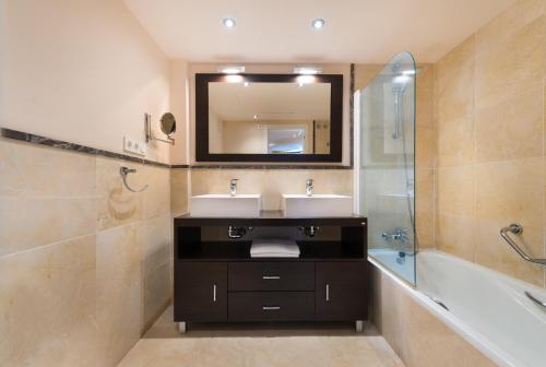 uma casa de banho com 2 lavatórios, um espelho e uma banheira em Fantástico apartamento de 1 dormitorio frente al mar em Torrox Costa