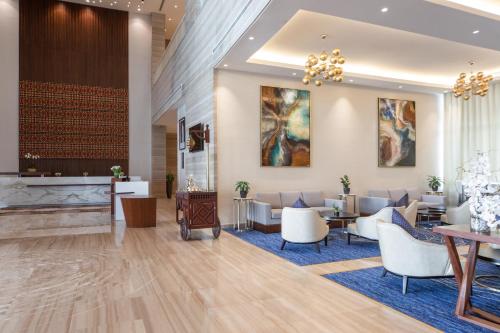 a lobby of a hotel with chairs and tables at dusitD2 Salwa Doha in Doha