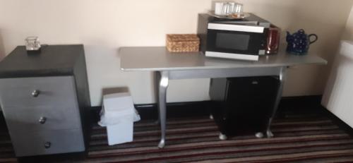 a room with a desk with a microwave and a table at The Saracens Head Old Lounge in Skegness