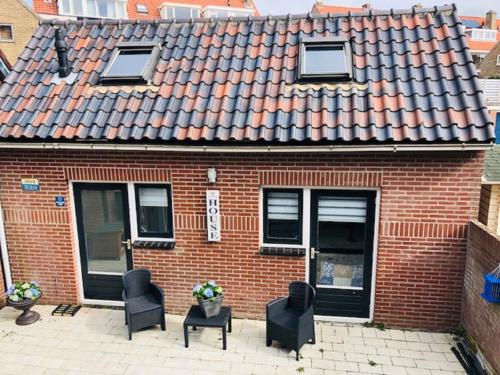 a red brick house with chairs and a table at Have a nice stay! - Blue Beach House 350 meters from sea in Noordwijk aan Zee