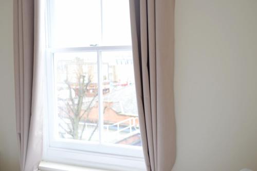 an open window with a view of a building at London's Central East End 2 Bedroom City Apartments in London