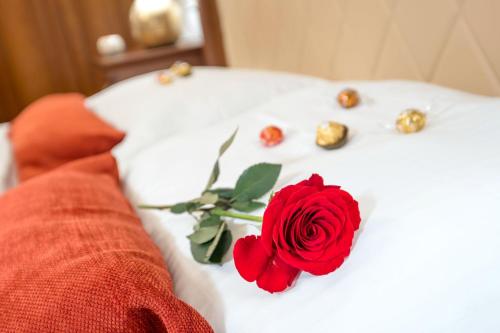 a red rose on a white bed with gold pins at Hotel & Restoran Dvorac Gjalski in Zabok