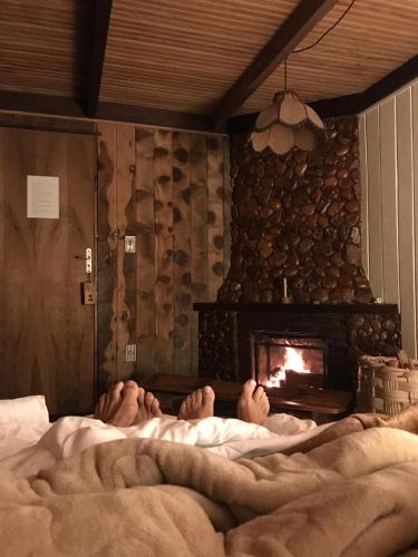 two people laying in bed in front of a fireplace at Hotel Refazenda in Visconde De Maua