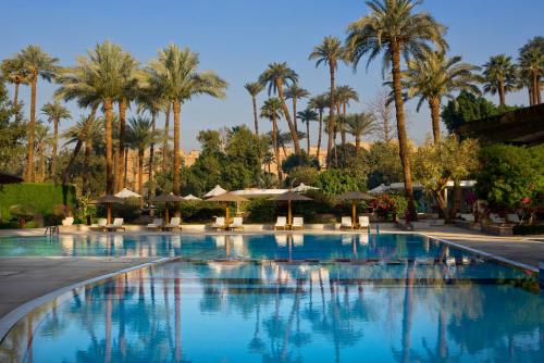 a large swimming pool with palm trees and umbrellas at Pavillon Winter Luxor in Luxor