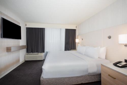 a hotel room with a large white bed and a television at Crowne Plaza Kansas City Downtown by IHG in Kansas City