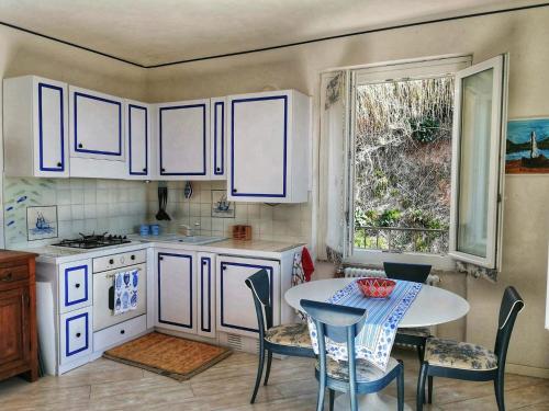 a kitchen with white cabinets and a table and a window at L'oblò in Riomaggiore