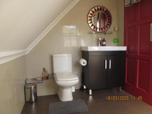 baño con aseo y lavabo y puerta roja en Luxury Secure Flat Apartment en Plattekloof