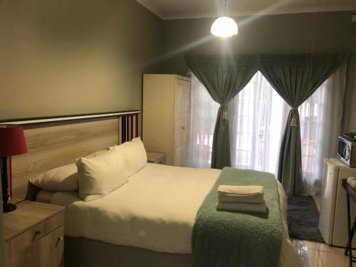 a bedroom with a large white bed and a window at Ndzuti Guest House in Witbank
