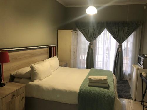 a bedroom with a large bed and a window at Ndzuti Guest House in Witbank