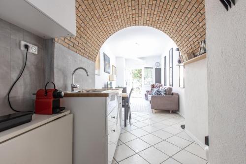 une cuisine avec une arche et des placards blancs dans l'établissement ,,La Chaumière d’Azur”, à Roquebrune-Cap-Martin