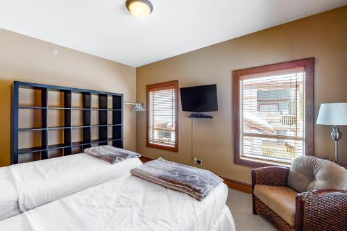 a bedroom with two beds and a chair and a tv at Spyglass 4C in Big White