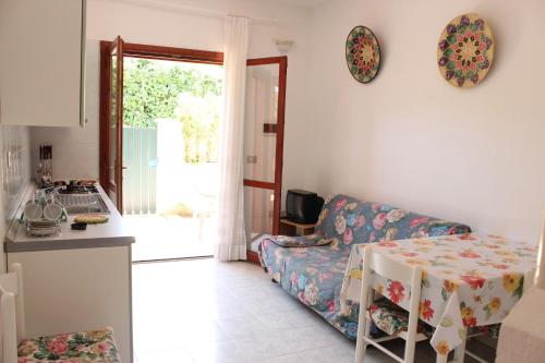 a kitchen and a living room with a couch and a table at Residenza Mediterranea in Villasimius