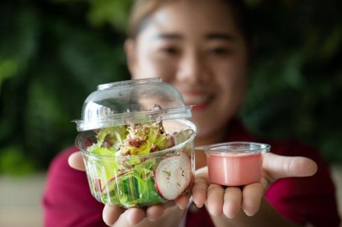 a woman is holding a salad in a glass jar at PLAAI Plus Hotel Rayong in Rayong