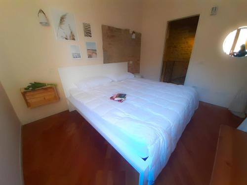 een slaapkamer met een wit bed met een boek erop bij La Casina del Porto in Fano