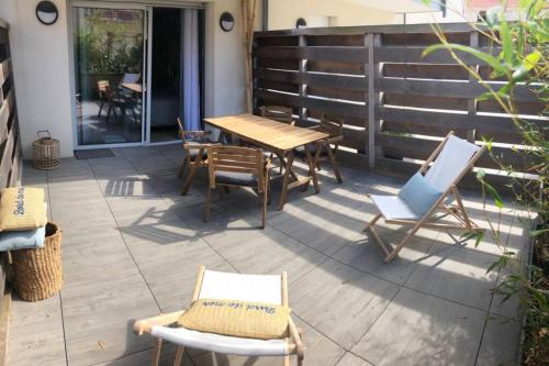 a patio with a wooden table and chairs at Un cocon zen les pieds dans l'eau à Hardelot in Neufchâtel-Hardelot