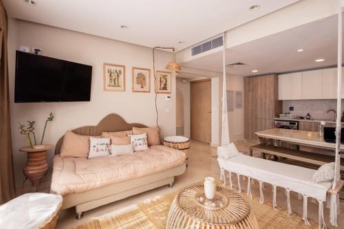 ein Wohnzimmer mit einem Sofa und einer Küche in der Unterkunft Gleaming 1 BR Apt Mangroovy w Pool & Beach Access in Hurghada