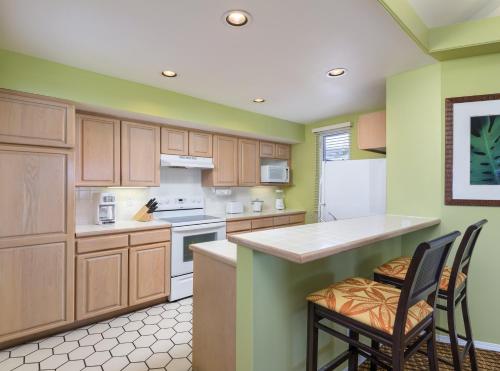 a kitchen with wooden cabinets and white appliances at Holua Resort in Kailua-Kona