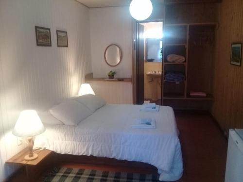 a bedroom with a bed with two lamps and a mirror at Hotel Refazenda in Visconde De Maua