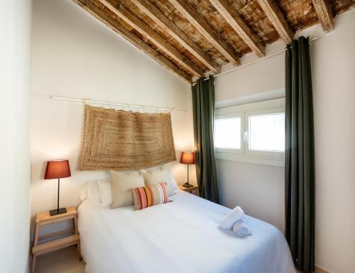 1 dormitorio con 1 cama blanca y 2 ventanas en Apartamentos Juan de Padilla, en Málaga