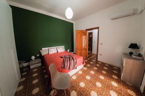 una camera da letto con una parete verde, un letto e una sedia di Civico 53 a Castro di Lecce