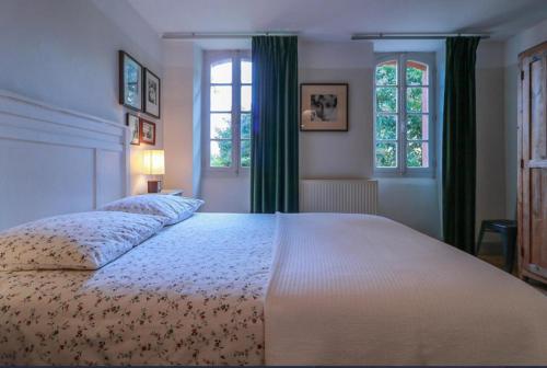 a bedroom with a large bed and two windows at L'Apouticayre in Montaut
