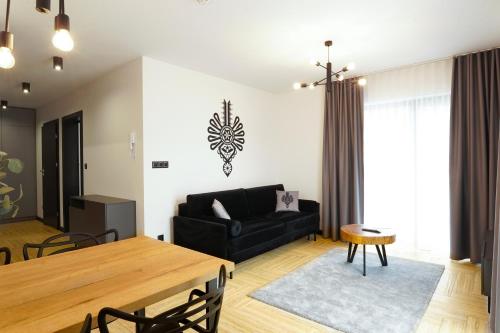a living room with a black couch and a table at Stylchyn 90 Apartamenty nad Jeziorem Czorsztyńskim in Kluszkowce