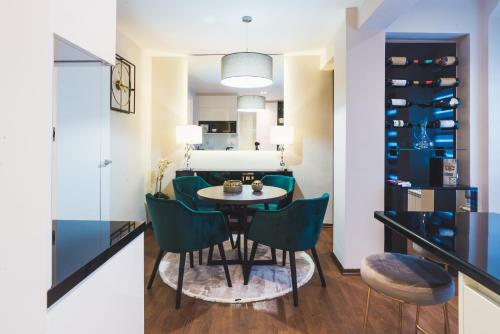 雅戈丁那的住宿－Majestic Apartment，一间带桌子和绿色椅子的用餐室