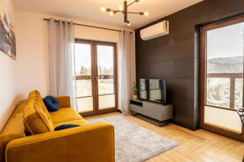 a living room with a couch and a television at Stylchyn 90 Apartamenty nad Jeziorem Czorsztyńskim in Kluszkowce
