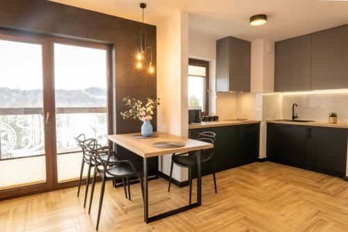 a kitchen with a table and chairs in a room at Stylchyn 90 Apartamenty nad Jeziorem Czorsztyńskim in Kluszkowce